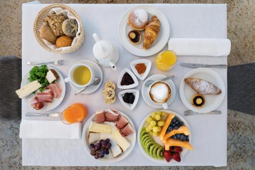 a table with plates of breakfast foods and drinks at Hotel Sporting Trento in Trento