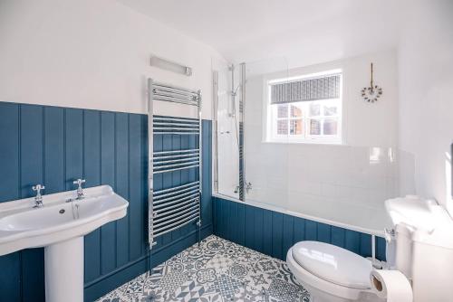 a blue and white bathroom with a sink and a toilet at Bonheur in Southwold