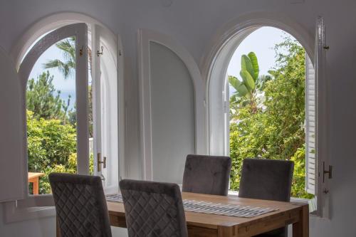 een eetkamer met gebogen ramen en een houten tafel en stoelen bij Villa Mila Mi in Benajarafe