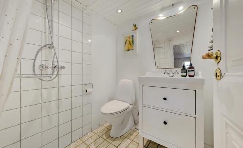 uma casa de banho branca com um WC e um espelho. em Hyggeligt gammelt fiskerhus i Marstal em Marstal