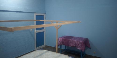 a blue room with a wooden rail and a table at Maison Charlotte Forever Chambre d'hôtes chez un couple belgo togolais in Lomé