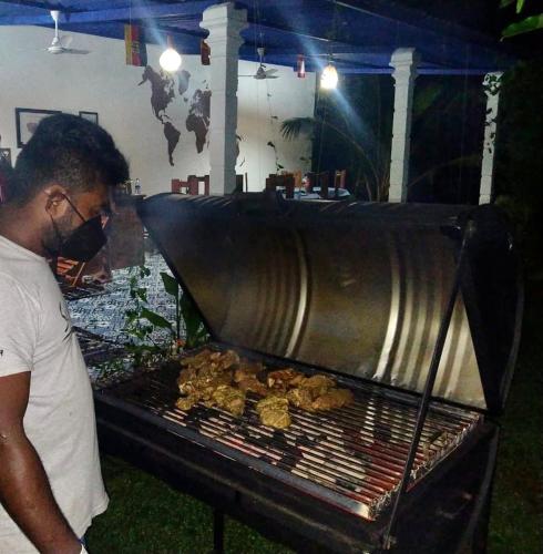 a man is cooking food on a grill at Sapphire Garden Hotel in Habarana
