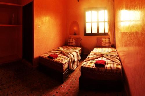 two twin beds in a room with a window at Villa Paradise in Aghmat