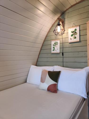 uma cama numa casa minúscula com duas almofadas em Tan-y-Dderwen Pod em Machynlleth