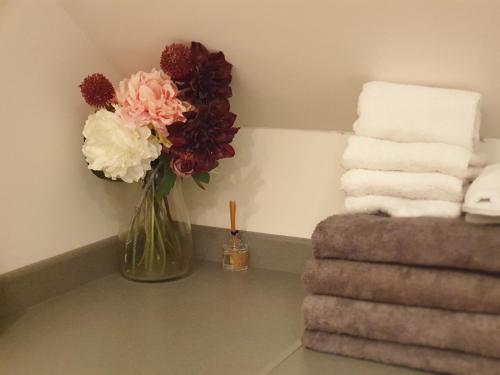 a vase of flowers on a table next to towels at New Bury Cottage near Goodwood in Chichester