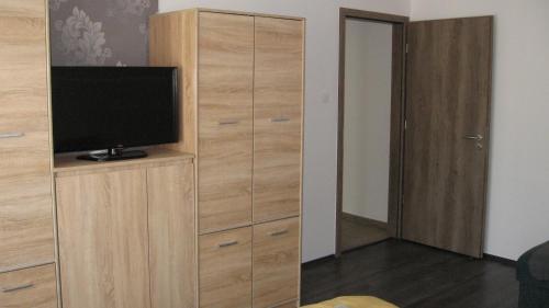 a living room with a television and a wooden cabinet at HZ Apartman Miskolc in Miskolc