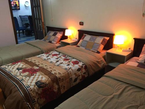 three beds in a room with two lamps at Al Marwa Apartment in Dokki - Families Only in Cairo