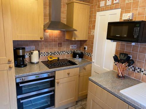 a kitchen with a stove and a microwave at Cosy 2 Bedroom House -2023, 2024 &2025 award winner! in Ramsgate