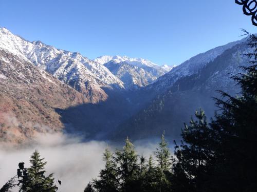 a view of a mountain range with clouds in the foreground at Kudrat - A Boutique Homestay- Tirthan Valley in Banjār