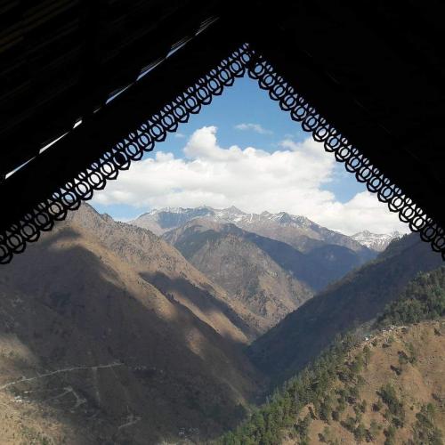 a view of a mountain range from a window at Kudrat - A Boutique Homestay- Tirthan Valley in Banjār
