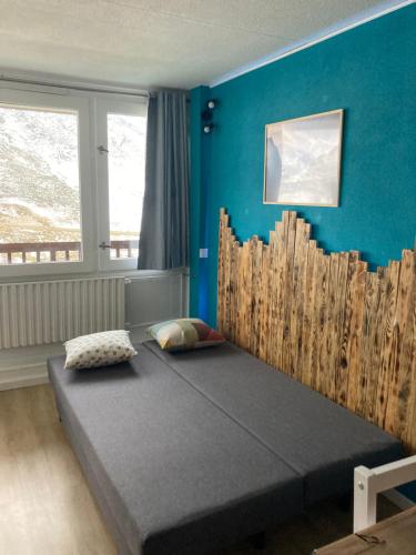 Cama en habitación con pared azul en Studio mongie aux pieds des pistes avec balcon, en La Mongie