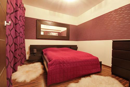 1 dormitorio con cama roja y espejo en ApartSerwis - Apartament Paryski, en Zakopane