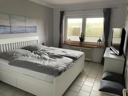 um quarto com uma cama e uma janela em Freundliche Ferienwohnung direkt hinter dem Deich em Friedrichskoog