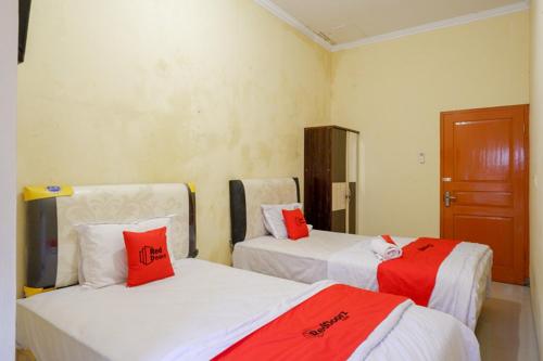 two beds in a room with red pillows on them at RedDoorz near Sleman City Hall 3 in Yogyakarta