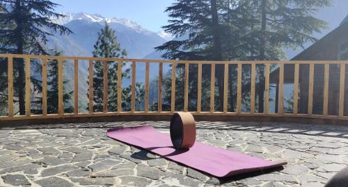 a pink yoga mat sitting on a patio with a bench at Kudrat - A Boutique Homestay- Tirthan Valley in Banjār