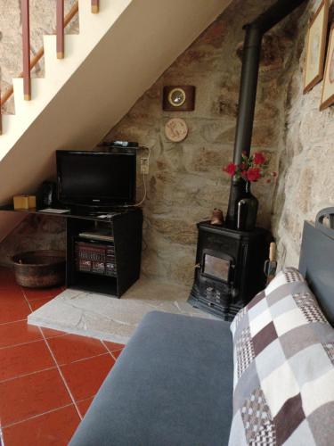 a living room with a tv and a wood stove at Casa do Palheiro in Montalegre