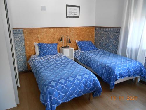 two beds in a hotel room with blue comforter at Sinos Rio Tinto in Campainha