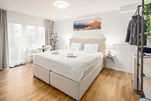a white bedroom with a large bed and a table at EH Apartments Mars in St. Gallen