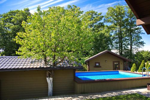 a swimming pool with a tree next to a house at Resort Baure in Palanga