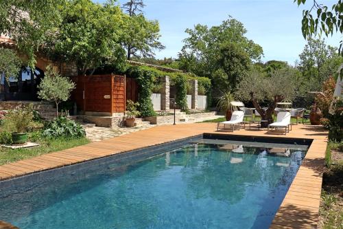 una piscina en un patio con 2 tumbonas en L Amourier chambres d hôtes pour amoureux avec Jacuzzi ou baignoire XXL, en Saint-Hippolyte-du-Fort