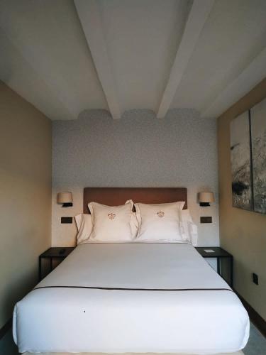 a bedroom with a large white bed with two pillows at Hotel Boutique Casa del Comendador in Navalcarnero