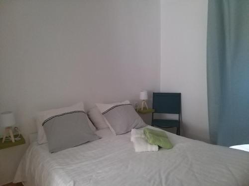 Bett mit weißer Bettwäsche und Kissen in einem Zimmer in der Unterkunft Rez de jardin cosy avec terrasse fleurie in Arles-sur-Tech
