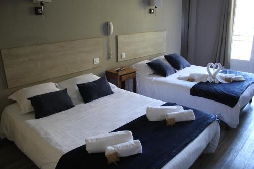 twee bedden in een hotelkamer met handdoeken erop bij Hôtel de La Beauronne in Chancelade