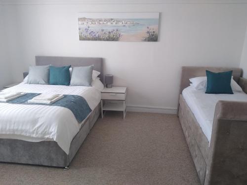 a bedroom with two beds with blue pillows at 45 New Esplanade Court in Paignton