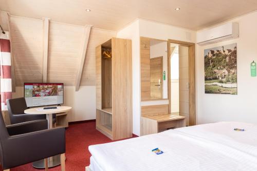 a bedroom with a bed and a desk with a computer at Hotel-Restaurant Straussen in Harburg