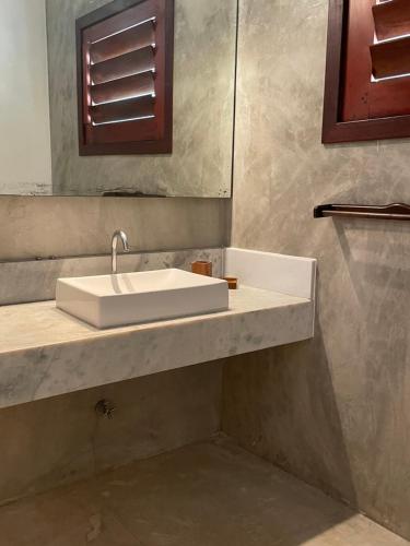 een badkamer met een witte wastafel en een spiegel bij App Lory KiteVillage in Uruau