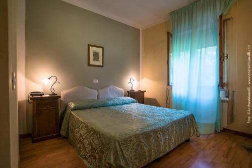 a bedroom with a bed and two lamps and a window at Hotel Relais Valle Orientina in Pitigliano