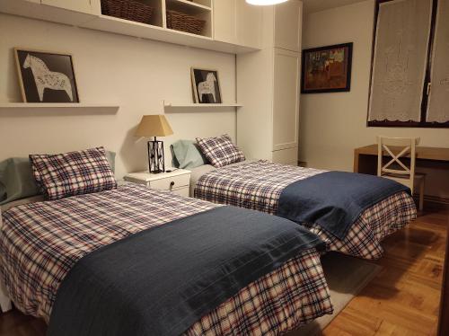 a bedroom with two beds and a table with a lamp at Dúplex en Parque Europa in Ezcaray