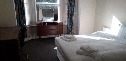a bedroom with a bed and a dresser and a mirror at Bird Song Guest House Old Trafford in Manchester