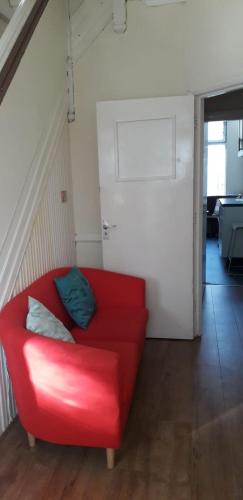 a red couch with two pillows on it in a room at Bird Song Guest House Old Trafford in Manchester