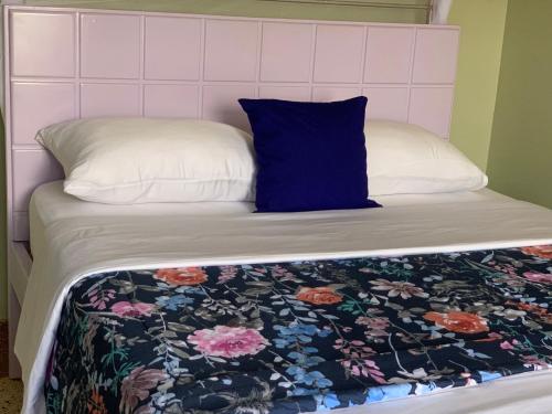 a bed with a blue pillow and a floral blanket at Yonny’s Citadel in Jinja