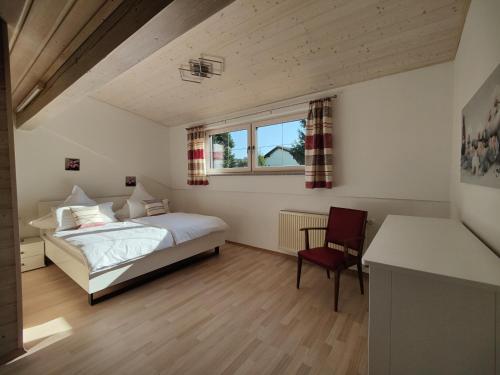 a bedroom with a bed and a chair and a window at Auszeit-Wohnungen in Aidenbach