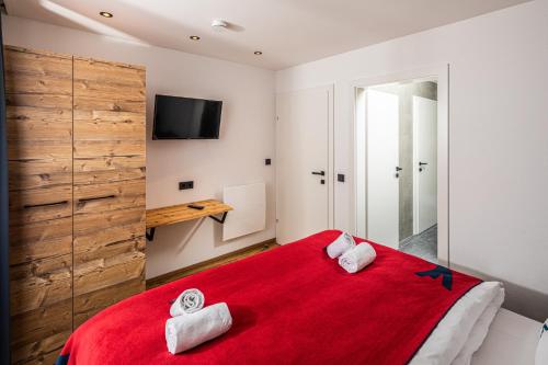 Falcon Suites Kaprun في كابرون: غرفة نوم بسرير احمر عليه مناشف