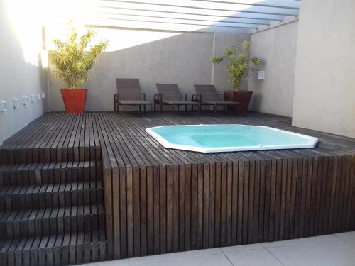a hot tub on a wooden deck with chairs at Acomodação Tranquila (Centro de Campos) in Campos dos Goytacazes