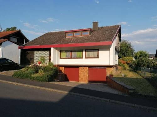 una casa bianca e rossa con garage rosso di Ferienwohnung Fröhlich a Dorfprozelten