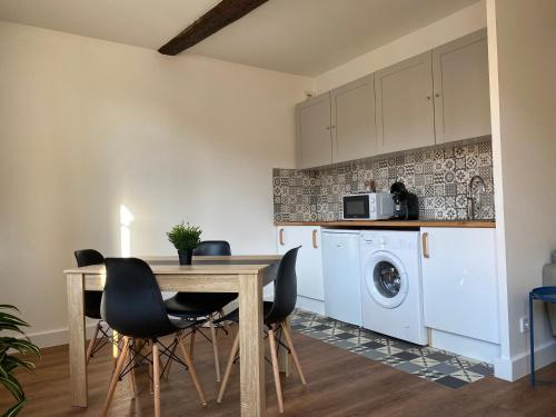 une cuisine avec une table et des chaises ainsi qu'un lave-linge dans l'établissement « Quartier des arts » de vivre à la Toulonnaise, à Toulon