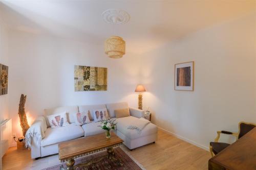 ein Wohnzimmer mit einem weißen Sofa und einem Tisch in der Unterkunft Les Suites d'Aliénor-Suite Acanthe in Pessac