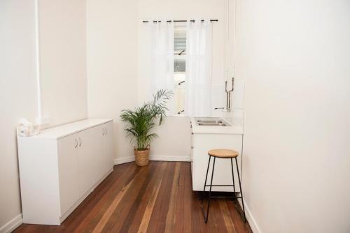 a kitchen with white cabinets and a wooden floor at The Met Hotel in Toowoomba