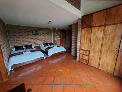a bedroom with two beds and a brick wall at Balcon al Cotopaxi Hosteria in Sangolquí