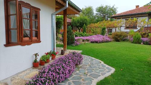 een tuin met paarse bloemen naast een huis bij Babinata Kashta-Srebarna in Srebŭrna