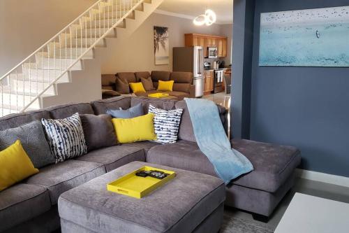 a living room with a gray couch with yellow pillows at Ubuntu De La Villa- Palm View Estate in Mammee Bay