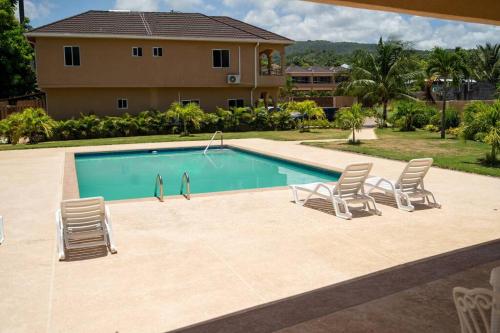 a swimming pool with chairs and a house at Ubuntu De La Villa- Palm View Estate in Mammee Bay