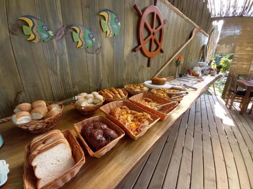 um bufê de pães e doces sobre uma mesa de madeira em Pousada Kaetê em Paraty