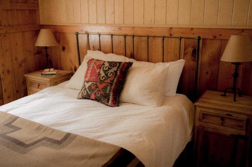 a bed with white sheets and a pillow on it at Beyul Retreat in Meredith