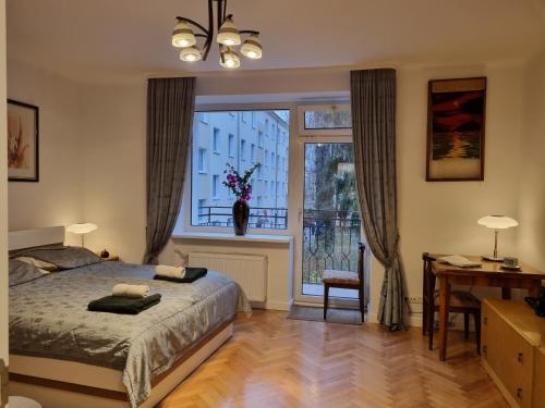 a bedroom with a bed and a window and a desk at W Kolorze Mięty in Warsaw