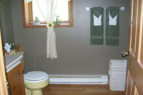 a bathroom with a toilet and a window and towels at La Belle Époque in La Malbaie